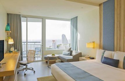 Holiday Inn Pattaya room with ocean view. Gay-friendly hotel with desk, chair, sofa, and balcony. Modern design for gay men travelers.