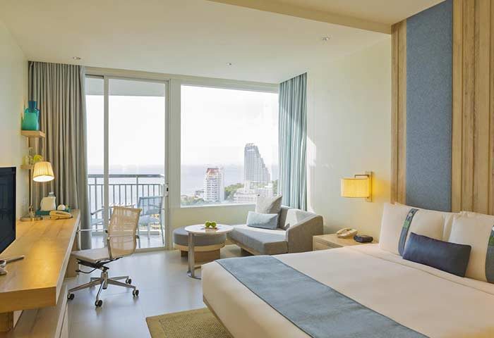 Holiday Inn Pattaya room with ocean view. Gay-friendly hotel with desk, chair, sofa, and balcony. Modern design for gay men travelers.