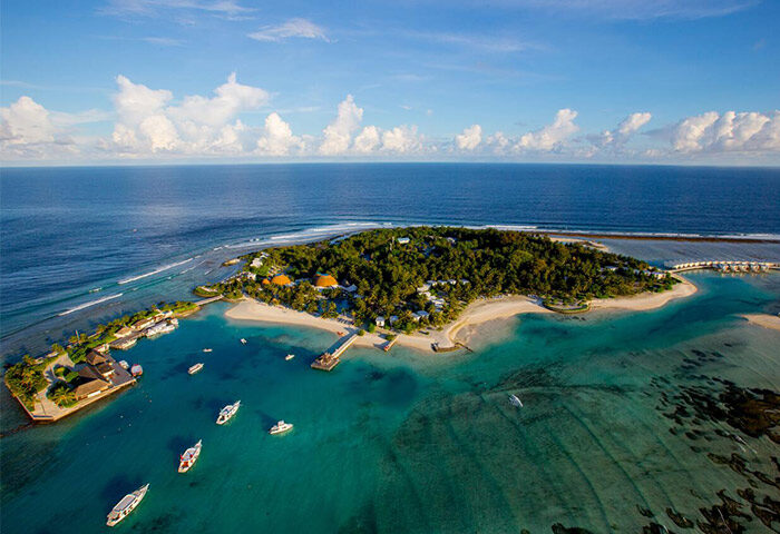 Aerial view of Holiday Inn Resort Kandooma Maldives, a gay-friendly hotel. Boats dot turquoise waters near the island's sandy beaches.