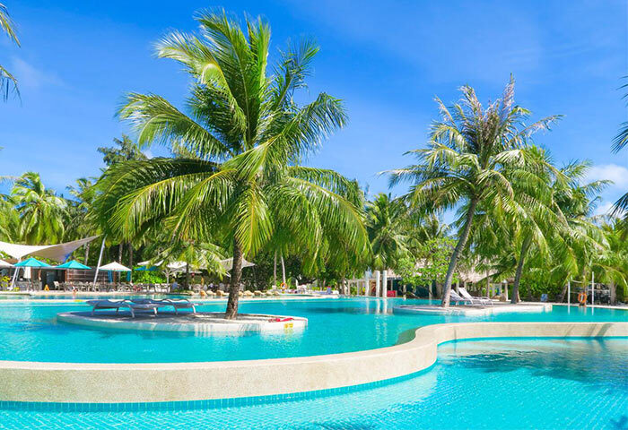 Holiday Inn Resort Kandooma Maldives pool view. Gay-friendly travel destination with palm trees and clear blue water.
