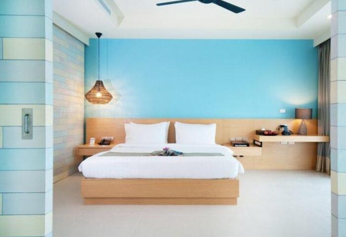 Holiday Inn Resort Krabi Ao Nang Beach gay-friendly hotel room. Modern design with blue wall, wooden bed frame, and ceiling fan.