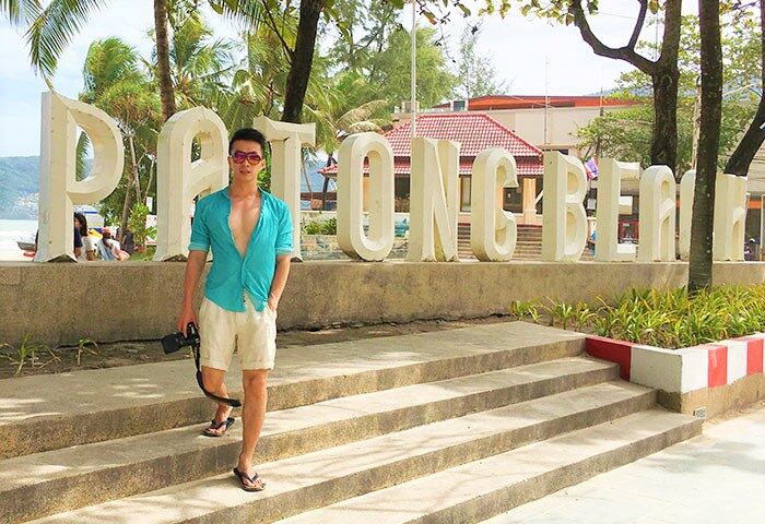 Gay traveler at Patong Beach sign, Phuket. Holiday Inn Resort Phuket is a gay-friendly hotel near this popular beach destination.