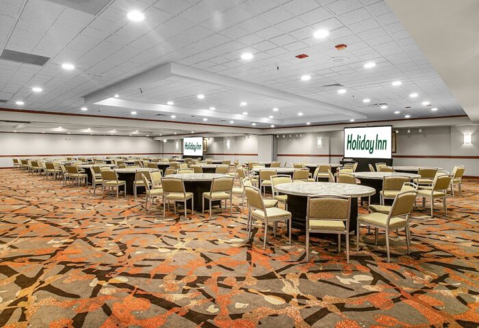 Ballroom at Gay-Friendly Holiday Inn San Francisco-Golden Gateway. Round tables with chairs, screens with the Holiday Inn logo.