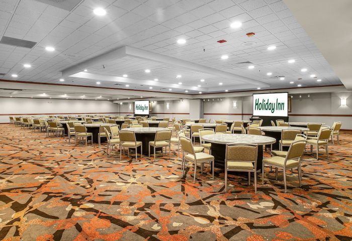 Ballroom at Gay-Friendly Holiday Inn San Francisco-Golden Gateway. Round tables with chairs, screens with the Holiday Inn logo.