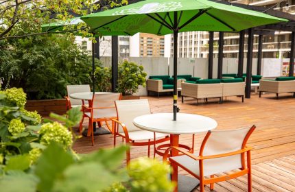 Holiday Inn Toronto Downtown Centre's patio. Gay-friendly hotel with outdoor seating, green umbrellas, tables, and chairs. Relaxing space.