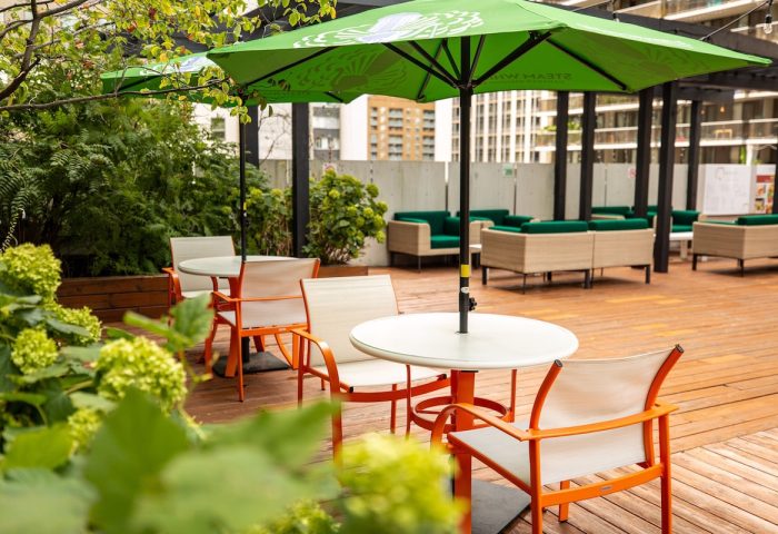 Holiday Inn Toronto Downtown Centre's patio. Gay-friendly hotel with outdoor seating, green umbrellas, tables, and chairs. Relaxing space.