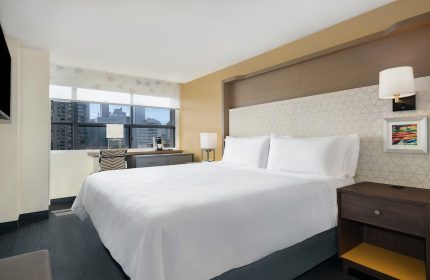 Holiday Inn Toronto Downtown Centre guest room. Modern interior with a large bed, desk, and city view. Gay-friendly hotel.
