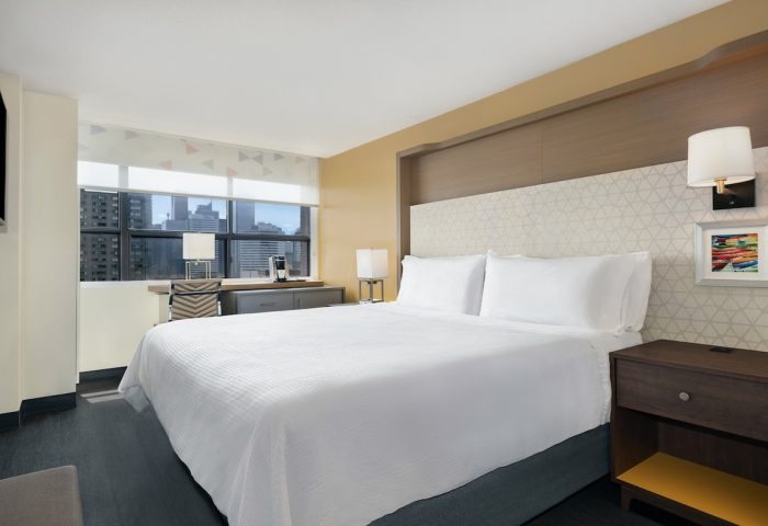 Holiday Inn Toronto Downtown Centre guest room. Modern interior with a large bed, desk, and city view. Gay-friendly hotel.