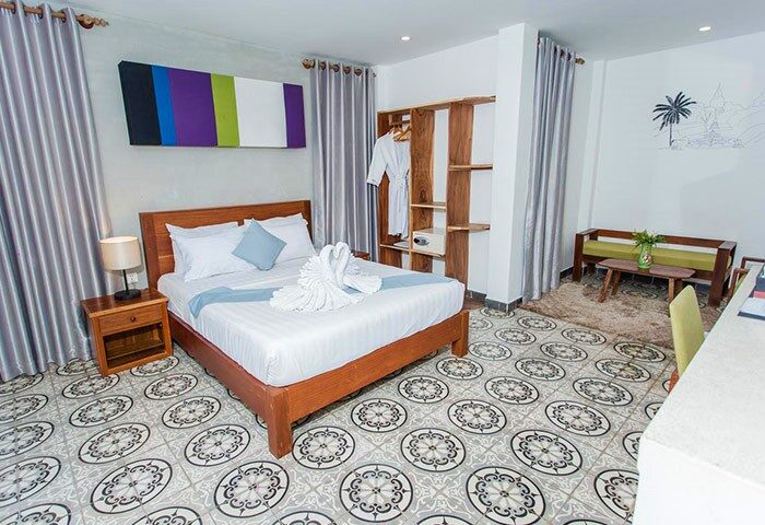 Home Chic Hotel's gay-friendly room: bed with swan towels, vibrant art, open closet, patterned floor. A welcoming space for gay travelers.