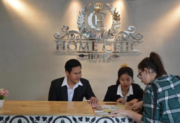 Home Chic Hotel reception. Staff assisting a guest. Gay-friendly hotel, offering travel advice for gay men. Welcoming atmosphere.