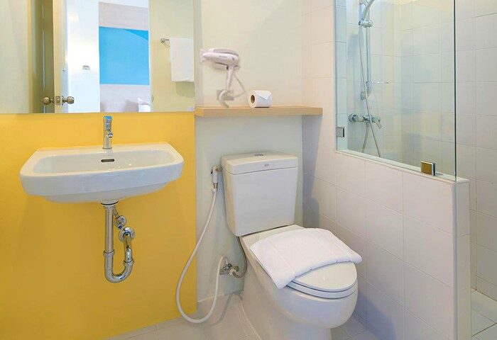 Bathroom at Hop Inn Hotel Ermita Manila, a gay-friendly hotel. Features a toilet, sink, shower, and hairdryer. Modern, clean design.
