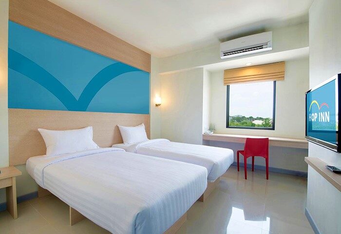 Gay-friendly Hop Inn Hotel Ermita Manila room. Twin beds, blue headboard design, TV, desk, and chair. Comfortable stay for gay travelers.