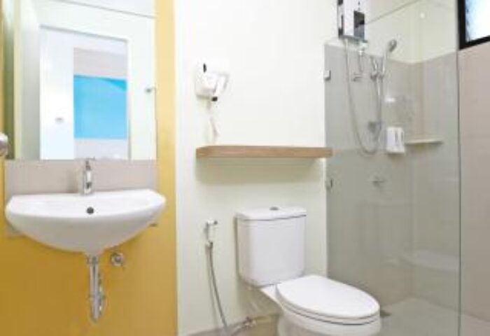 Bathroom interior at Hop Inn Hotel Ermita Manila, a gay-friendly hotel. Features include a sink, toilet, shower, and hairdryer. Clean, modern design.