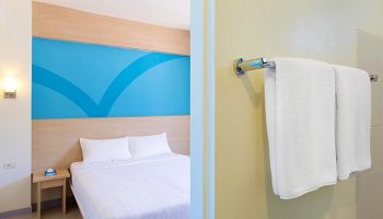 Hop Inn Hotel Makati Avenue Manila room. Gay-friendly hotel with bed, blue accent wall, bedside table, & bathroom towels. Manila travel.