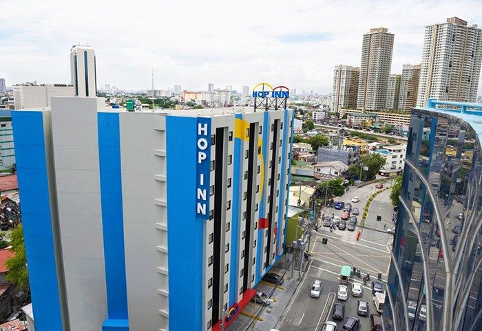 Hop Inn Hotel Makati Avenue Manila, a gay-friendly hotel in the Philippines. Exterior view of the hotel with city skyline in the background.