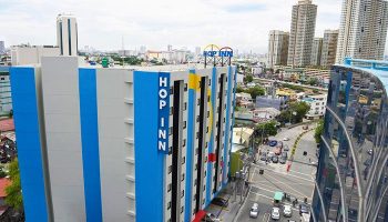 Hop Inn Hotel Makati Avenue Manila, a gay-friendly hotel in the Philippines. Exterior view of the hotel with city skyline in the background.