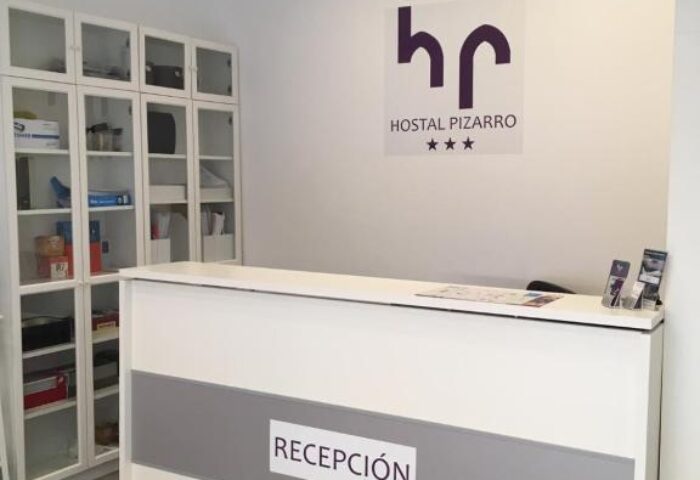 Reception area at Gay-Friendly Hotel Hostal Pizarro. Modern white desk with Recepción sign. Welcoming space for gay travelers.