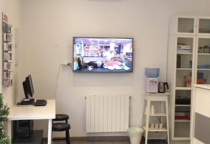 Hostal Pizarro's gay-friendly hotel room: TV, desk, stools, and a water cooler. Modern, clean design for gay men travelers.