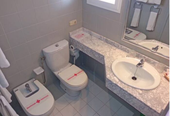 Bathroom at Gay-Friendly Hostal Residencia Molins Park. Toilet, bidet, sink, and mirror. Clean, tiled room. Gay travel accommodation.