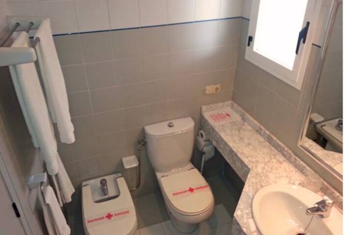 Bathroom interior at Gay-Friendly Hostal Residencia Molins Park. Toilet, bidet, sink, towels, and window visible. Clean and modern design.