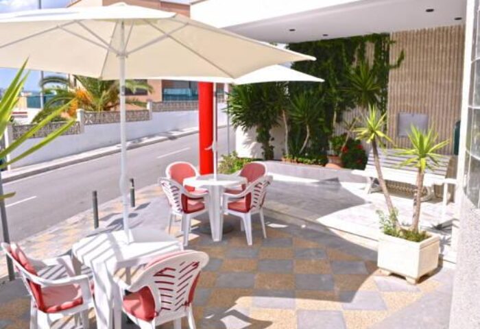 Outdoor seating at Gay-Friendly Hostal Residencia Molins Park. Tables with umbrellas, chairs, and plants create a welcoming space.