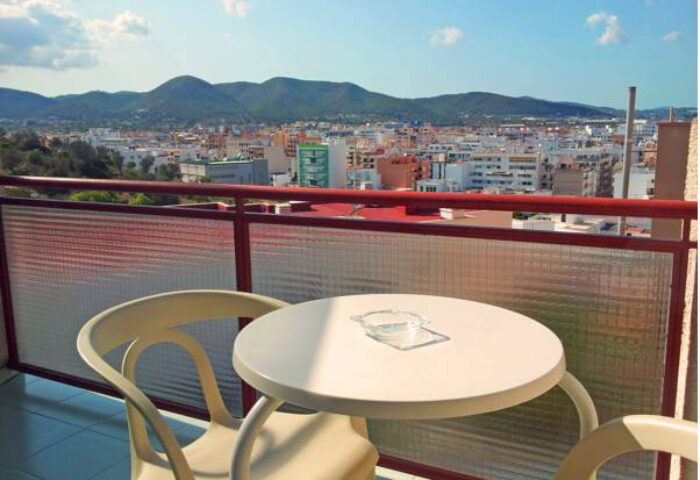 View from Hostal Residencia Molins Park's gay-friendly hotel balcony. Table and chairs overlook the city and mountains. Ideal for gay men travel.