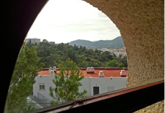 View from Hostal Residencia Molins Park, a gay-friendly hotel. Landscape with mountains, trees, and a building with a red roof.