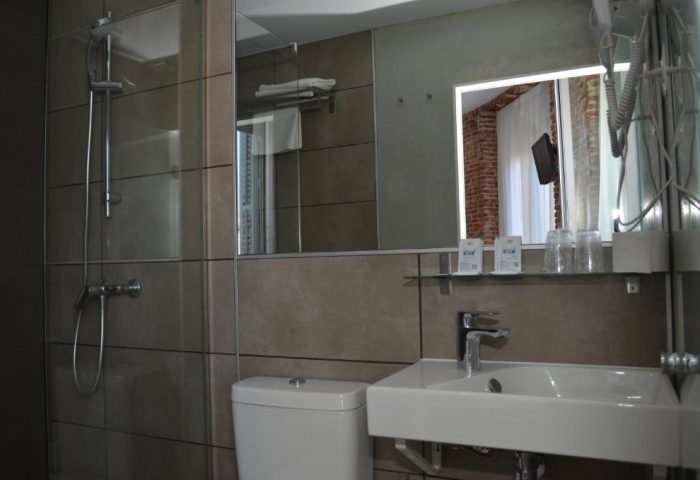 Bathroom at Gay-Friendly Hotel Hostal San Lorenzo. Shower, toilet, sink, and mirror. Modern design for gay travelers in Madrid.