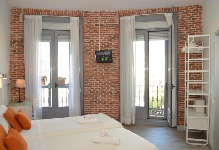 Gay-Friendly Hotel Hostal San Lorenzo room. Two beds, exposed brick, TV, balcony. Gay travel accommodations in Madrid, Spain.