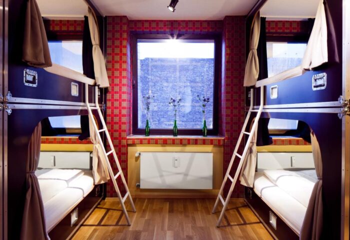 Hostel die Wohngemeinschaft room. Gay-friendly hotel with bunk beds, ladders, and a window. Unique hostel for gay travelers.