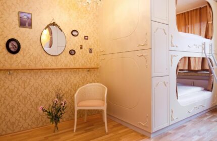Hostel die Wohngemeinschaft room featuring a chair, ornate wallpaper, and a unique bunk bed design. Gay-friendly hotel interior.