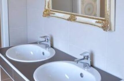 Bathroom with double sinks and ornate mirror at Gay-Friendly Hotel Hostel die Wohngemeinschaft, a top gay travel destination.
