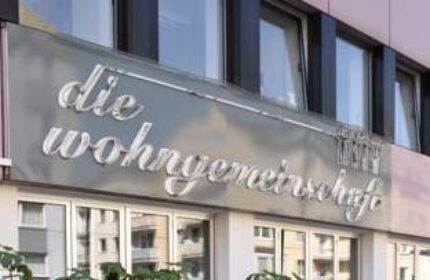 Hostel die Wohngemeinschaft facade. Gay-friendly hotel for gay men travel. Signage with die Wohngemeinschaft text. Modern building.