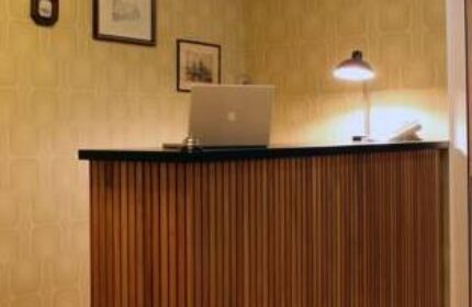 Die Wohngemeinschaft hostel reception desk. Gay-friendly hotel interior with laptop and lamp. A welcoming space for gay travelers.