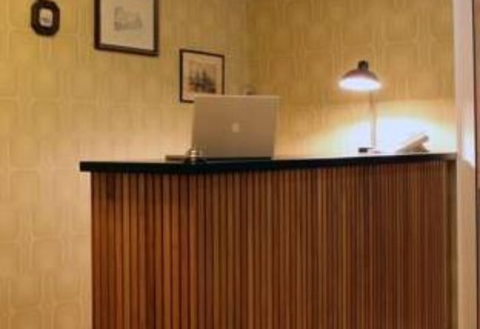 Die Wohngemeinschaft hostel reception desk. Gay-friendly hotel interior with laptop and lamp. A welcoming space for gay travelers.