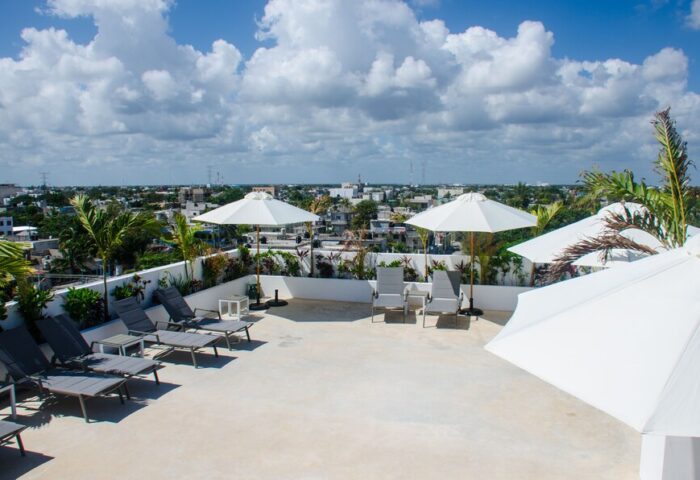 Hotel 52, a gay-friendly hotel. Rooftop terrace view with lounge chairs, umbrellas, and city skyline. Ideal for gay travelers' relaxation.