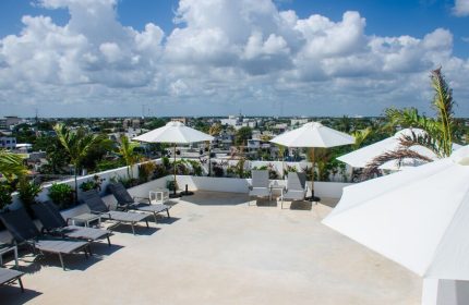 Hotel 52, a gay-friendly hotel. Rooftop terrace view with lounge chairs, umbrellas, and city skyline. Ideal for gay travelers' relaxation.