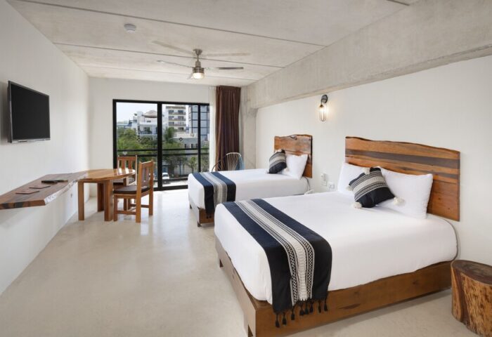 Hotel 52 gay-friendly hotel room with two beds, wooden headboards, table, chairs, and a view. Ideal for gay men travel in a stylish space.