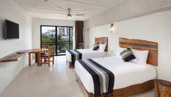 Hotel 52 gay-friendly hotel room with two beds, wooden headboards, table, chairs, and a view. Ideal for gay men travel in a stylish space.