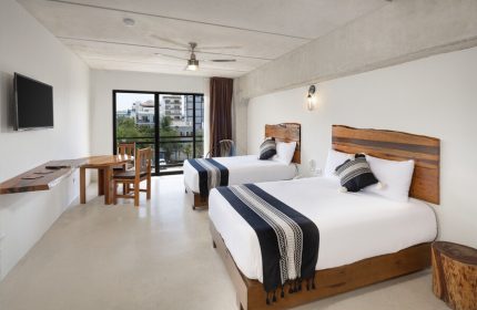 Hotel 52 gay-friendly hotel room with two beds, wooden headboards, table, chairs, and a view. Ideal for gay men travel in a stylish space.
