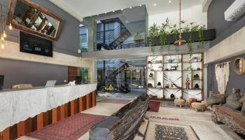 Hotel 52, a gay-friendly hotel. Unique lobby area with eclectic decor, plants, rugs, and interesting furniture. Hotel interior design.