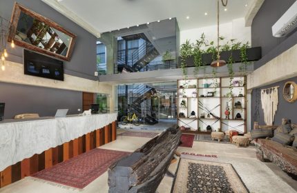 Hotel 52, a gay-friendly hotel. Unique lobby area with eclectic decor, plants, rugs, and interesting furniture. Hotel interior design.