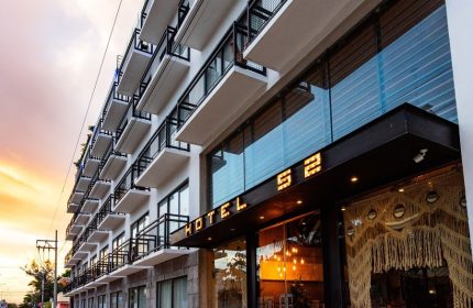 Hotel 52, a gay-friendly hotel. Exterior view of the hotel with balconies. The name Hotel 52 is lit above the entrance. Modern architecture.