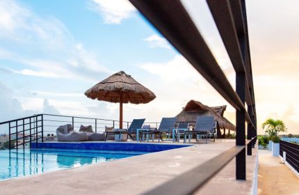 Hotel 52's gay-friendly rooftop pool with thatched umbrellas, lounge chairs, and beanbag chairs. A perfect gay travel destination.