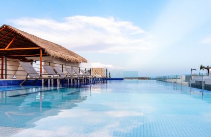 Hotel 52, a gay-friendly hotel. Infinity pool view with lounge chairs under a thatched roof. Perfect for gay travel and relaxation.