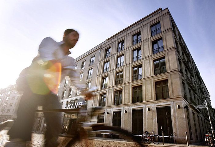 Hotel AMANO, a gay-friendly and pet-friendly hotel. Exterior view with a blurred cyclist passing by. Great for gay men travel advice.
