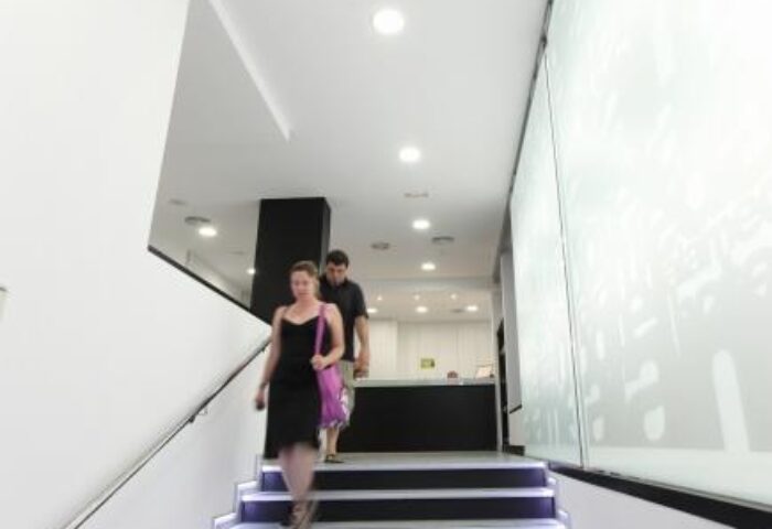 Couple at Hotel Alameda, a gay-friendly hotel. Modern interior with stairs leading to the reception. Great for gay travel advice.
