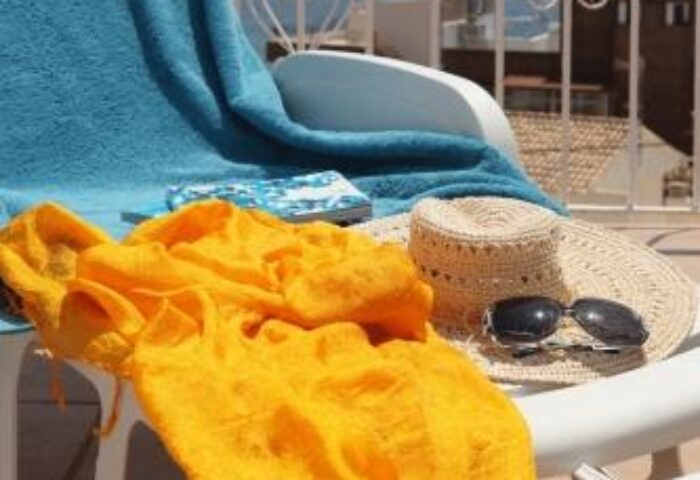 Hotel Alameda gay-friendly pool scene. Towel, hat, and sunglasses on a lounge chair. Perfect for gay travel and relaxation.