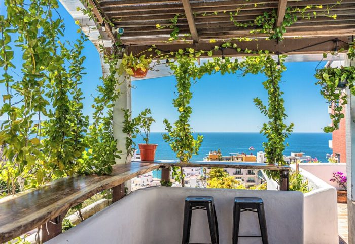 Hotel Amaca Puerto Vallarta Adults Only gay-friendly hotel view. Ocean view from the terrace with stools, plants, and a wooden bar.