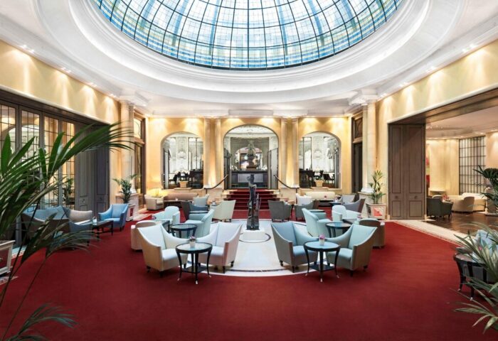 Hotel Bayerischer Hof's elegant lobby. A gay-friendly hotel with a stunning glass dome, seating, and red carpet. Luxury travel advice.